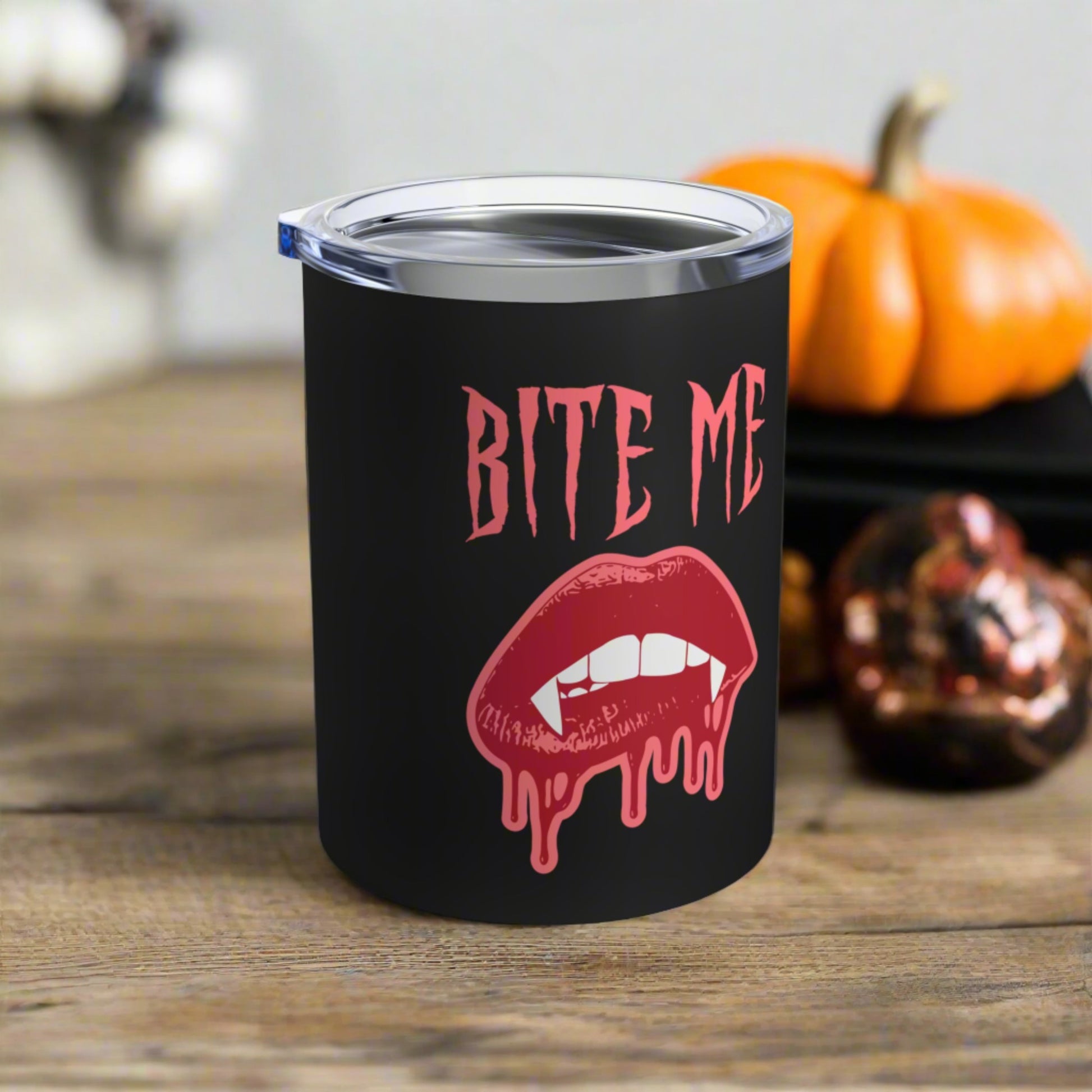 This 10 ounce stainless steel vacuum insulated black travel tumbler features vampire lips and fangs dripping with blood and the words Bite Me in Pink.