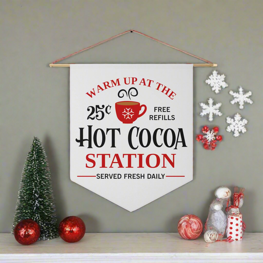 This white Christmas wall hanging banner flag says Warm Up At The Hot Cocoa Station Served Fresh Daily. Free Refills. It features a red cup.