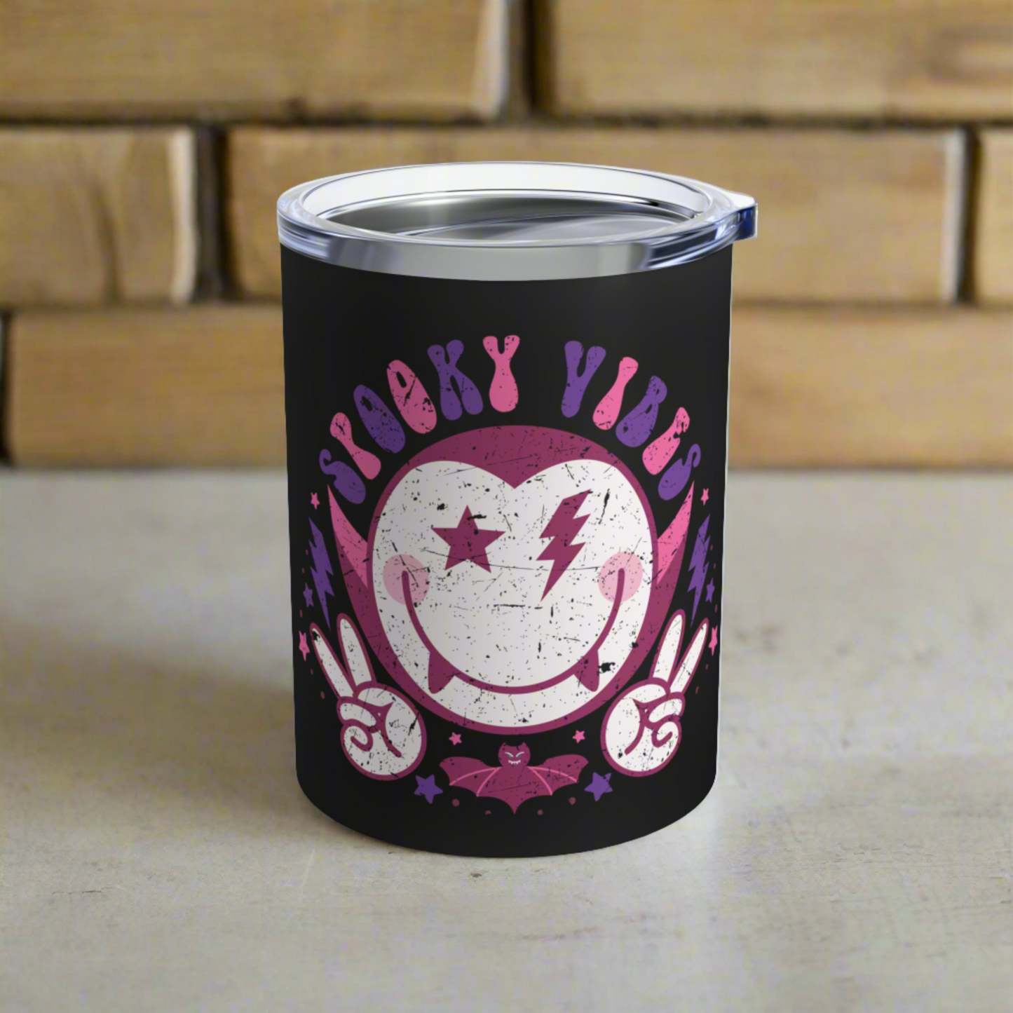 This 10 ounce stainless steel black travel tumbler mug features a distressed retro style illustration of Dracula and a bat that says Spooky Vibes.