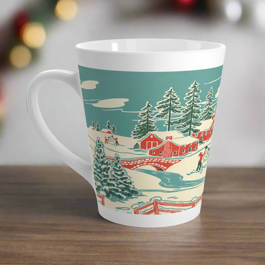 This ceramic glossy latte coffee mug features a vintage winter Christmas illustration of a snowy winter town. There are red houses, a bridge, trees, and two children building a snowman.