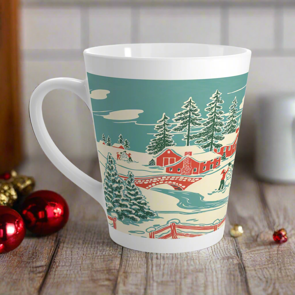 This ceramic glossy latte coffee mug features a vintage winter Christmas illustration of a snowy winter town. There are red houses, a bridge, trees, and two children building a snowman.