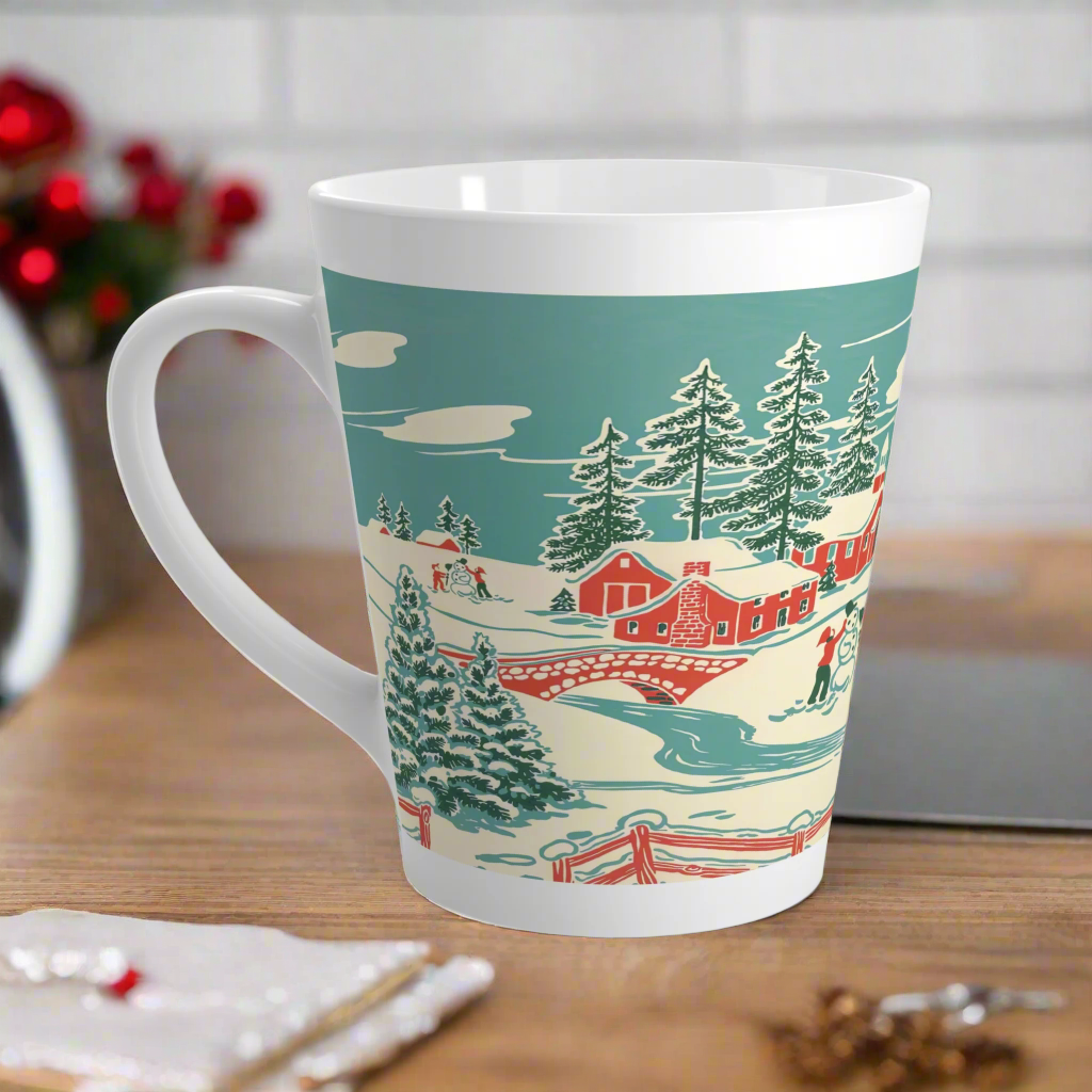 This ceramic glossy latte coffee mug features a vintage winter Christmas illustration of a snowy winter town. There are red houses, a bridge, trees, and two children building a snowman.