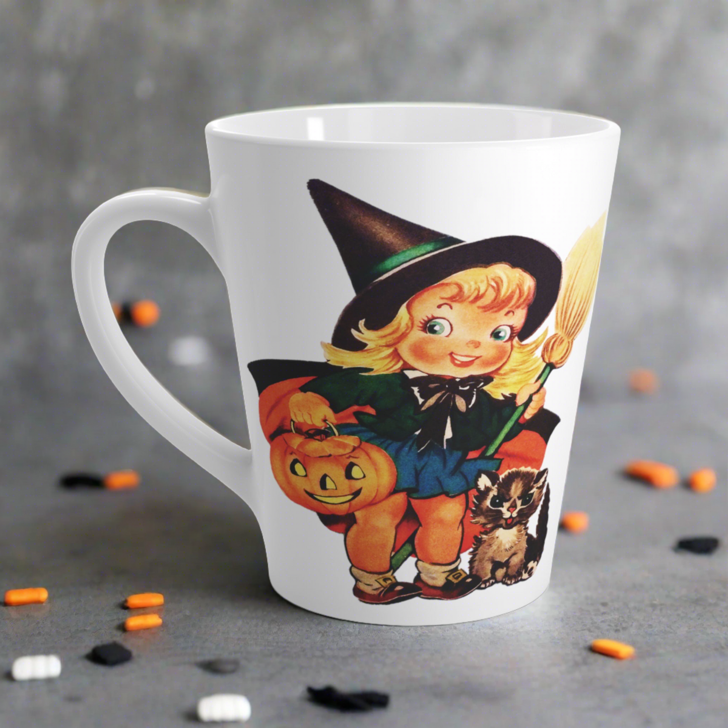 This ceramic glossy latte coffee cup features a retro vintage Halloween print of a young witch holding a broom and jack o lantern with a little brown cat sitting next to her.