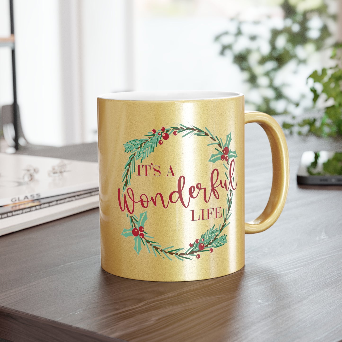 This gold metallic ceramic mug features a holly wreath with red lettering that says It's a Wonderful Life.