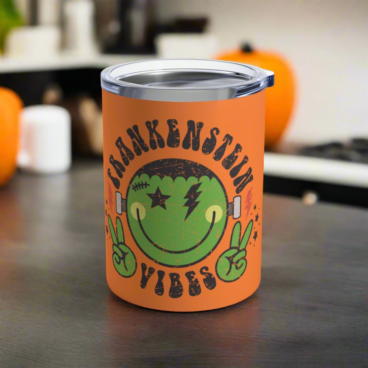 This 10 ounce orange stainless steel travel tumbler says Frankenstein Vibes and features a cute green monster smiley face with stars and lightning bolts.