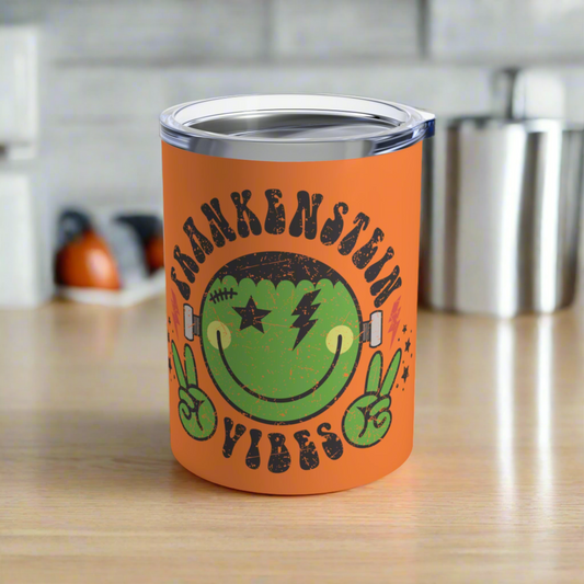 This 10 ounce orange stainless steel travel tumbler says Frankenstein Vibes and features a cute green monster smiley face with stars and lightning bolts.