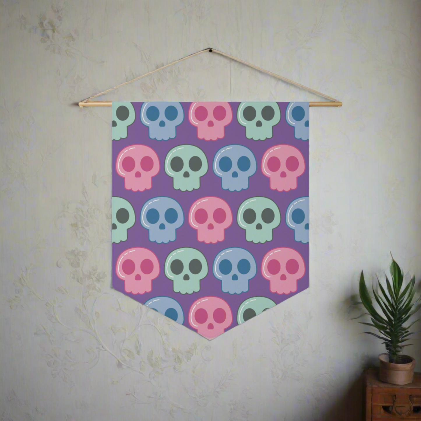 This fabric wall hanging features pastel skulls in pink, green and blue with a purple background. They are staggered in a pattern.