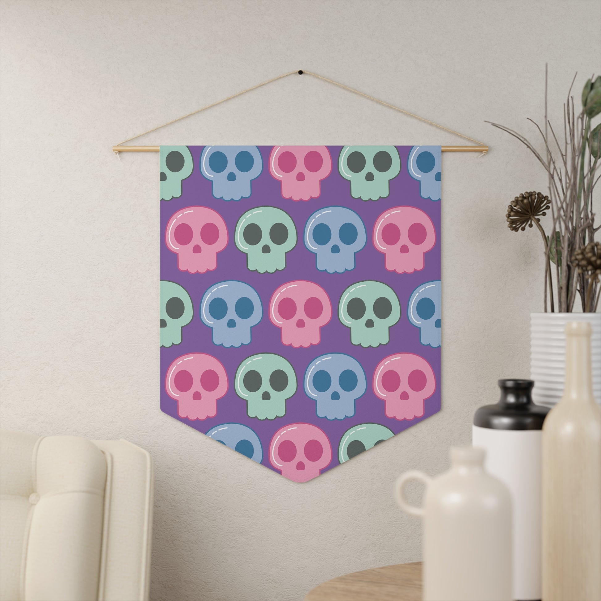 This fabric wall hanging features pastel skulls in pink, green and blue with a purple background. They are staggered in a pattern.