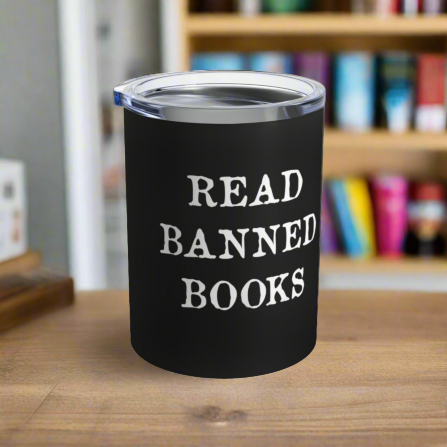 This 10 ounce black stainless steel insulated travel tumbler mug features white letters that say Read Banned Books. The tumbler comes with a plastic sipping lid.