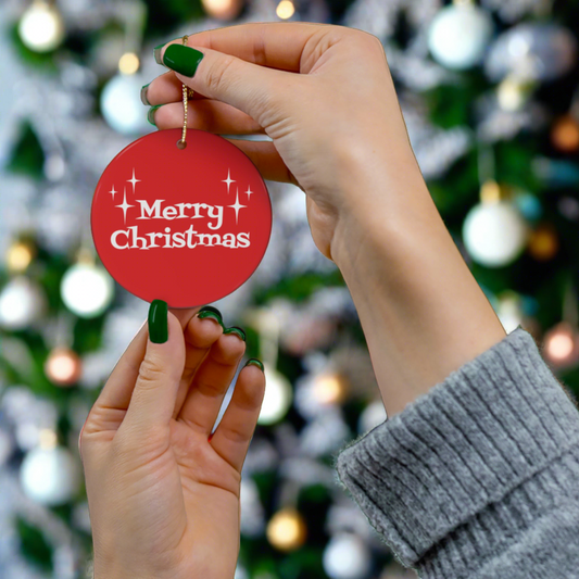 This round ceramic ornament is red with white atomic era style lettering that says Merry Christmas with three starbursts on each side.