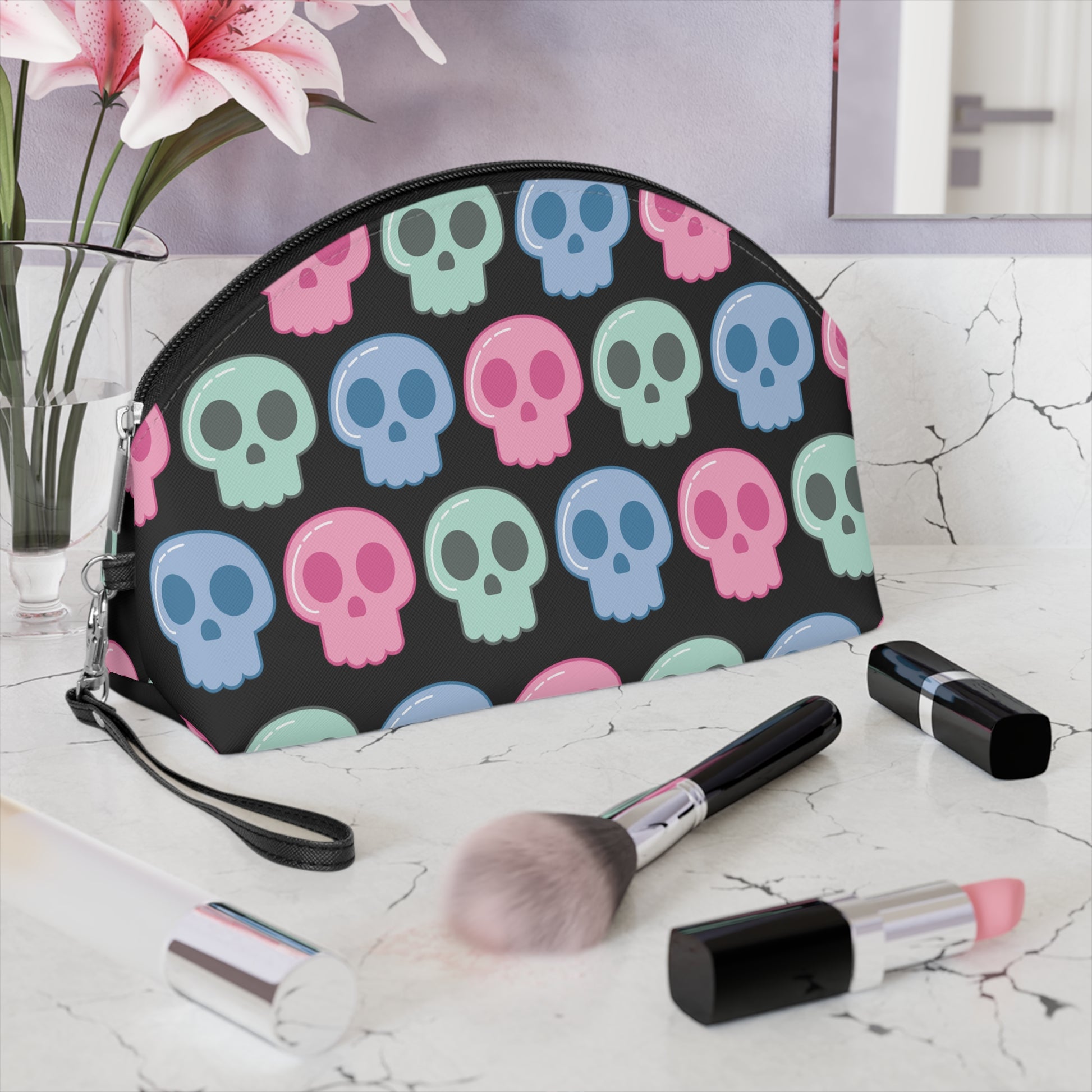 Cute cosmetic makeup travel bag featuring adorable pastel skulls with a black background. The bag has a zipper and a side wristlet.