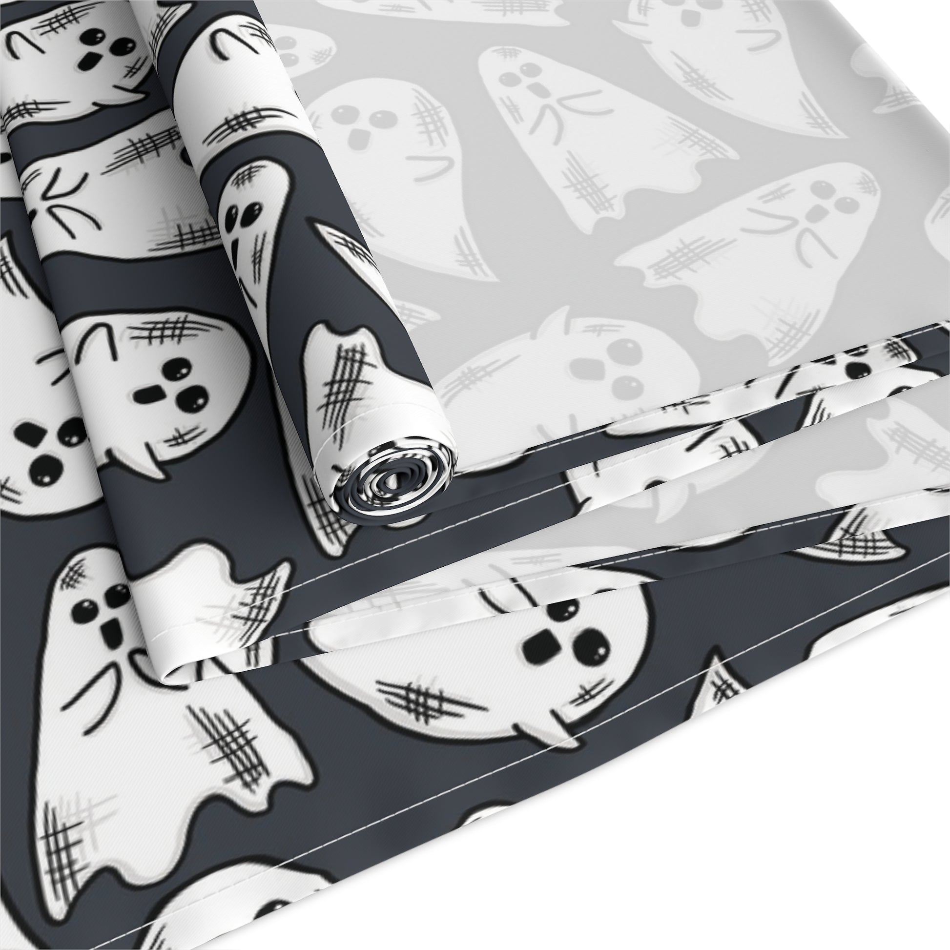 This Halloween table runner features adorable hand drawn ghosts patterned across the cloth with a dark grey background.