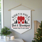 This white Christmas wall hanging pennant banner flag says North Pole Bed and Breakfast Warm Fire and Cozy Beds. It features a red house with trees and stars.