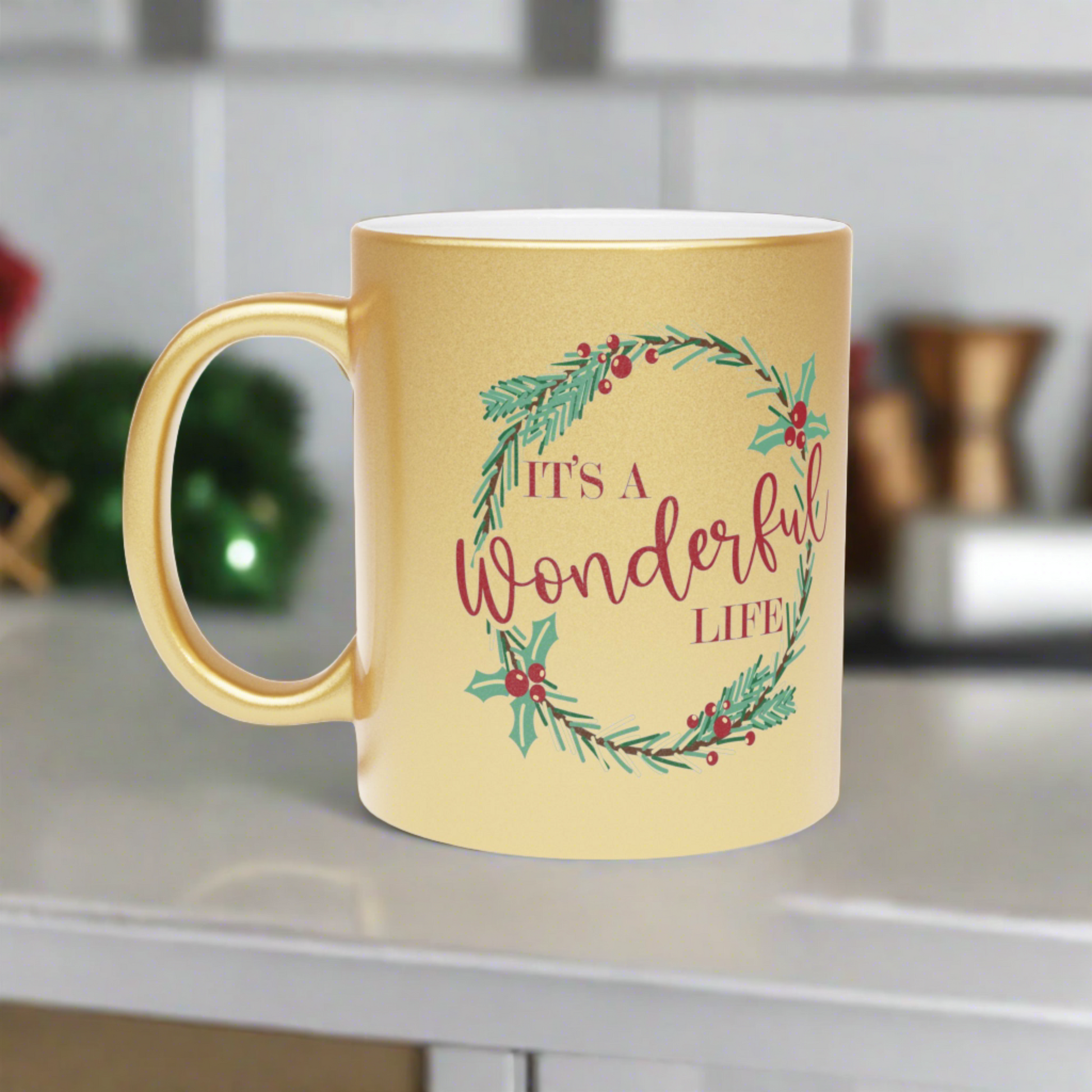 This gold metallic ceramic mug features a holly wreath with red lettering that says It's a Wonderful Life.