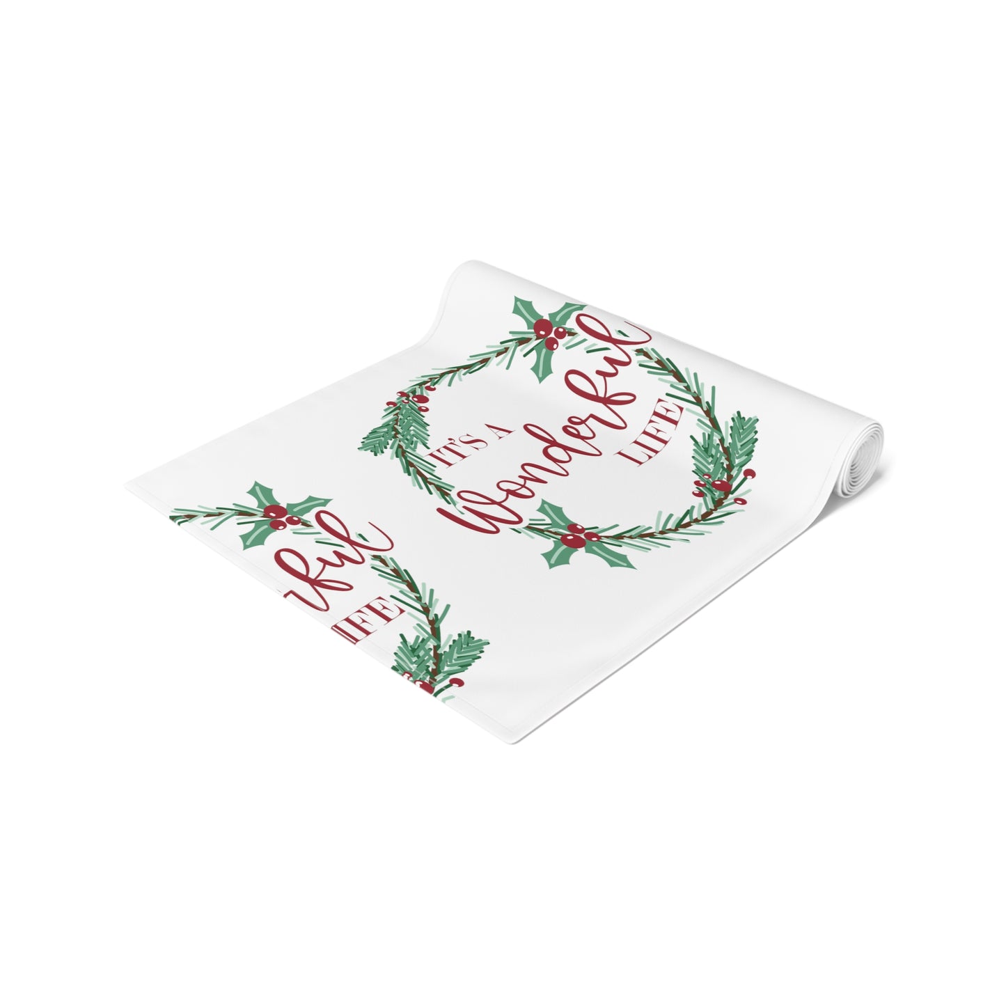 This white Christmas table runner features red lettering that says It's A Wonderful Life inside a holly berry wreath.