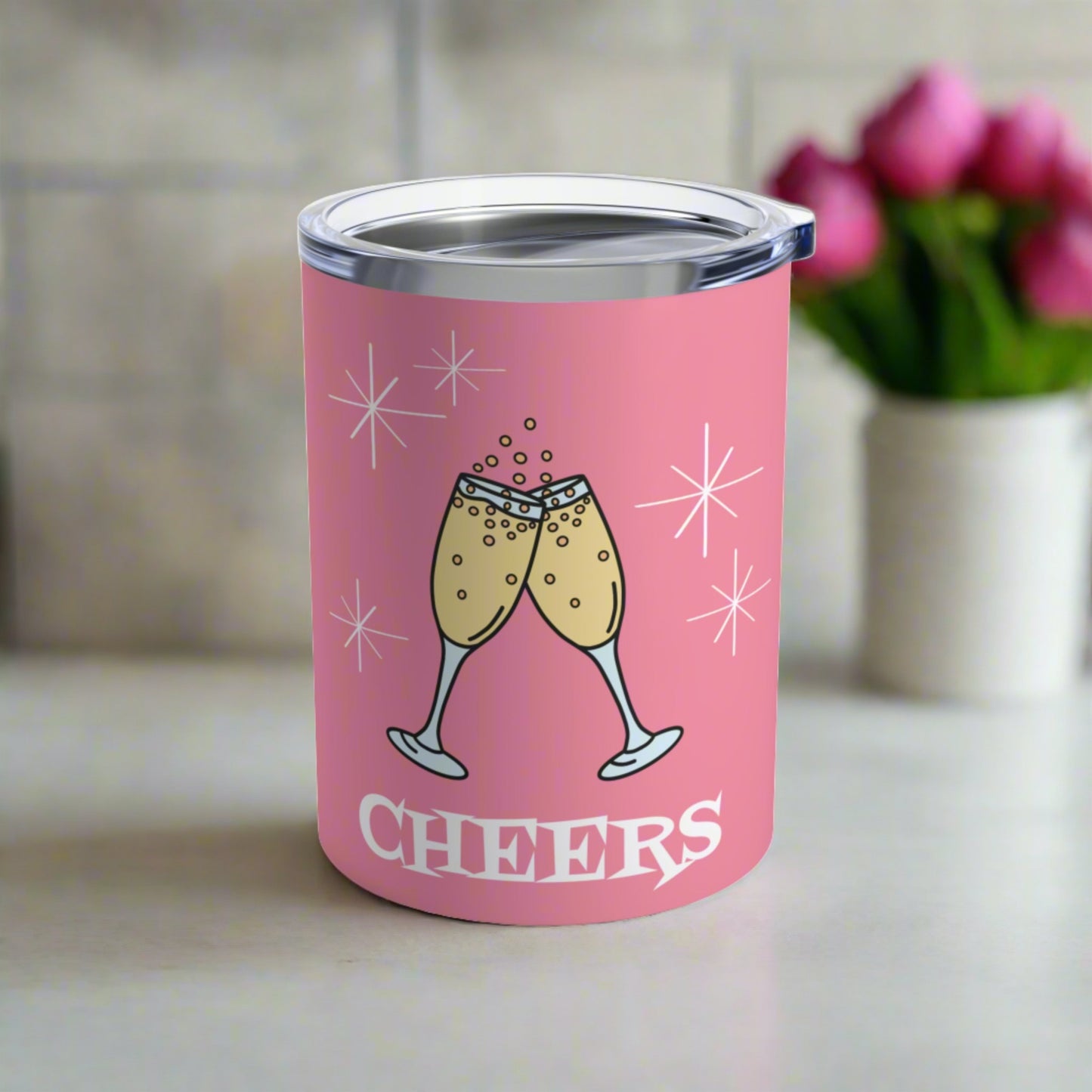 This 10 ounce pink stainless steel tumbler features two toasting champagne glasses with little bubbles. There is atomic era stars and lettering that says Cheers. It comes with a plastic sipping lid.