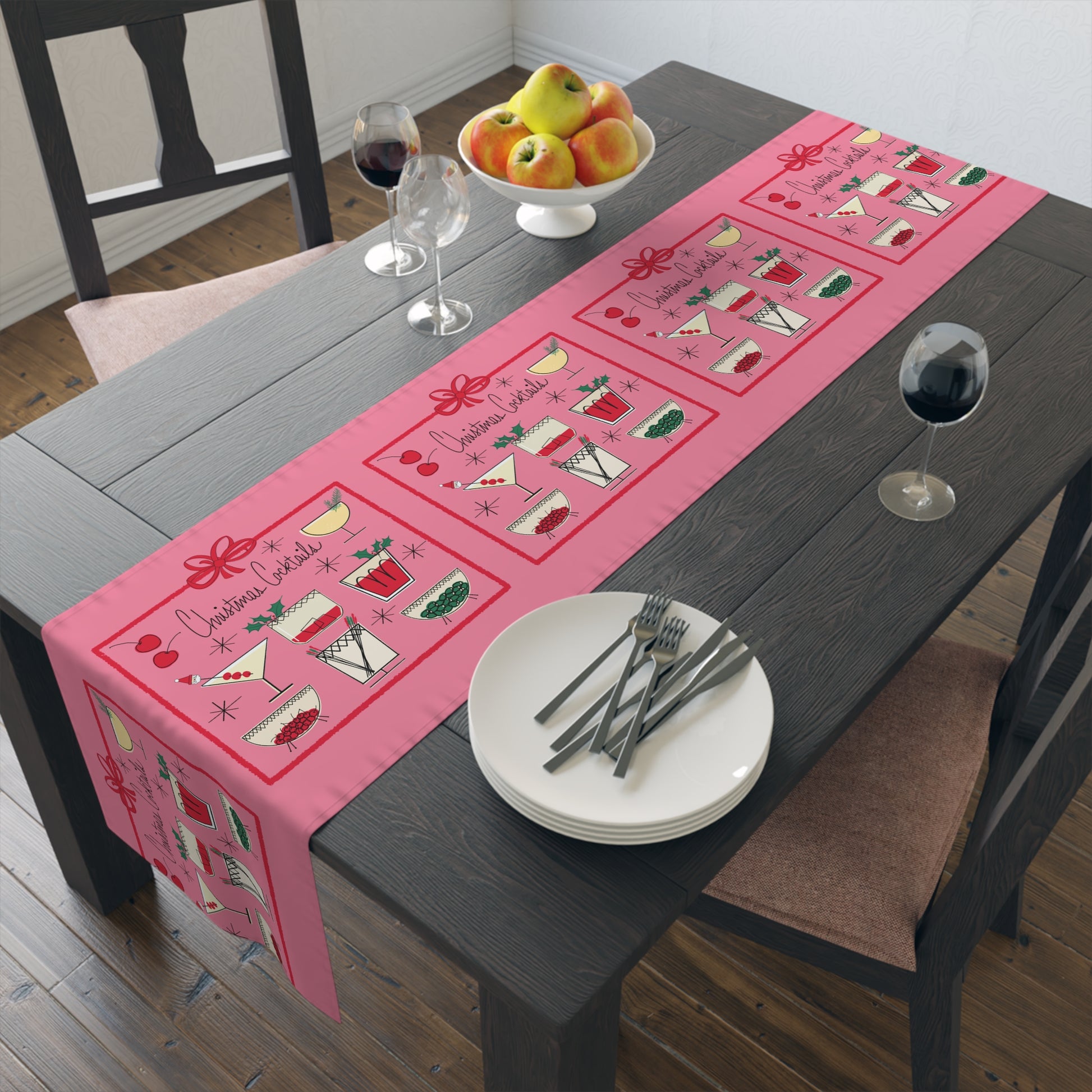 The pink Christmas table runner features the AriesCat Christmas Cocktails design. It features different midcentury style cocktails artwork with a red square present bow around them. 