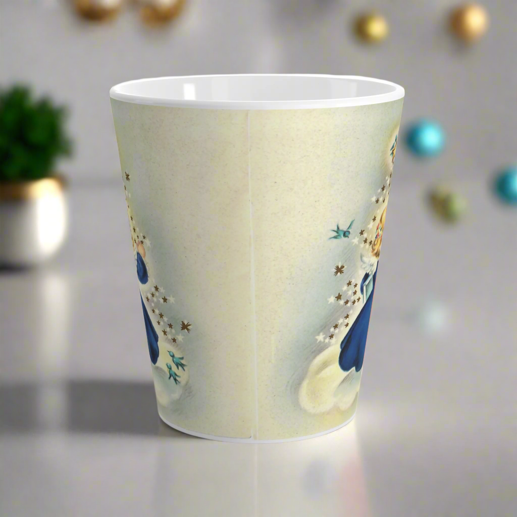 This ceramic glossy latte mug features an angel dressed in blue standing on a cloud. Her back is to us and you can see her wings. She is standing under a yellow star and bluebird. There are smaller white and blue stars and bluebirds surrounding her.