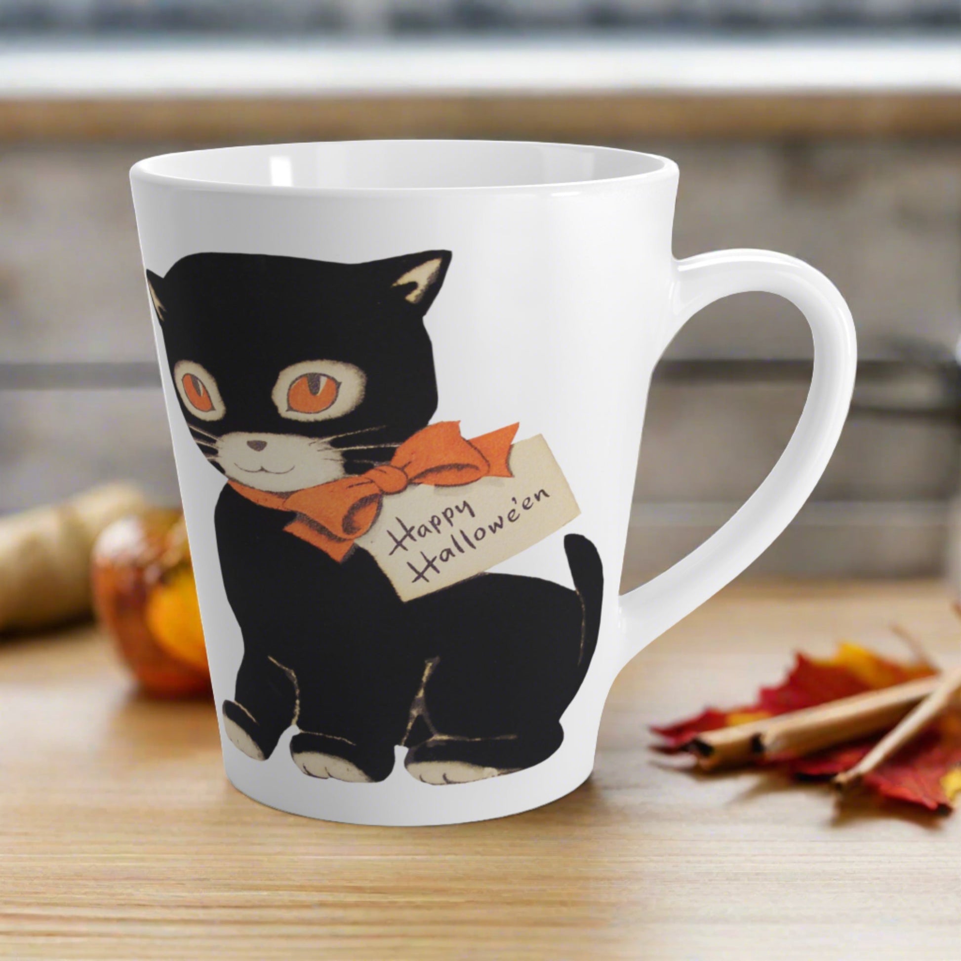 This glossy ceramic latte mug features a retro vintage Halloween illustration of a black cat with orange eyes. She is wearing an orange bow with a tag that says Happy Halloween.