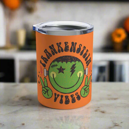 This 10 ounce orange stainless steel travel tumbler says Frankenstein Vibes and features a cute green monster smiley face with stars and lightning bolts.