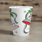 This ceramic glossy latte coffee cup features a vintage Christmas illustration of two holiday bells with ribbon, pine and berries. The design on the bells is reminiscent of European Scandinavian Christmas decorations.