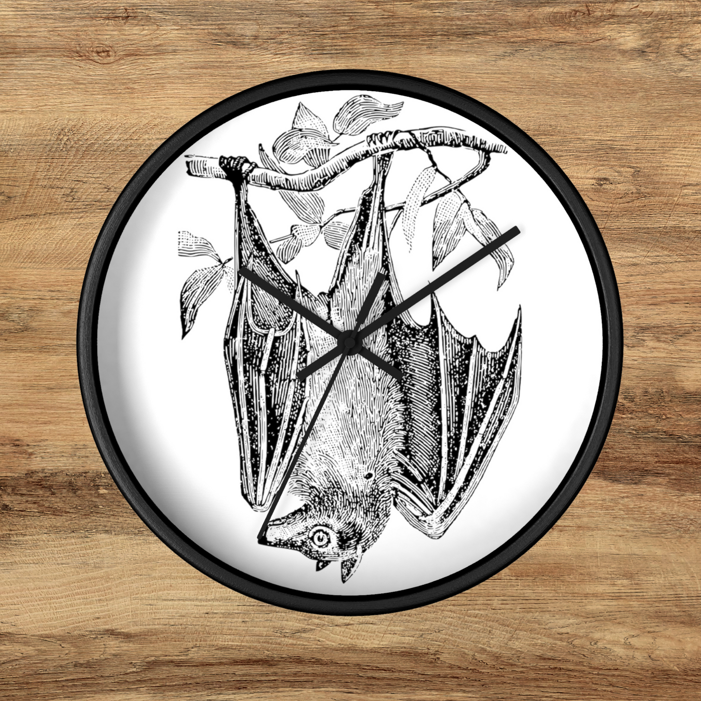 This black wall clock features a vintage illustration of a bat hanging upside down from a branch. The frame and hands of the clock are black.