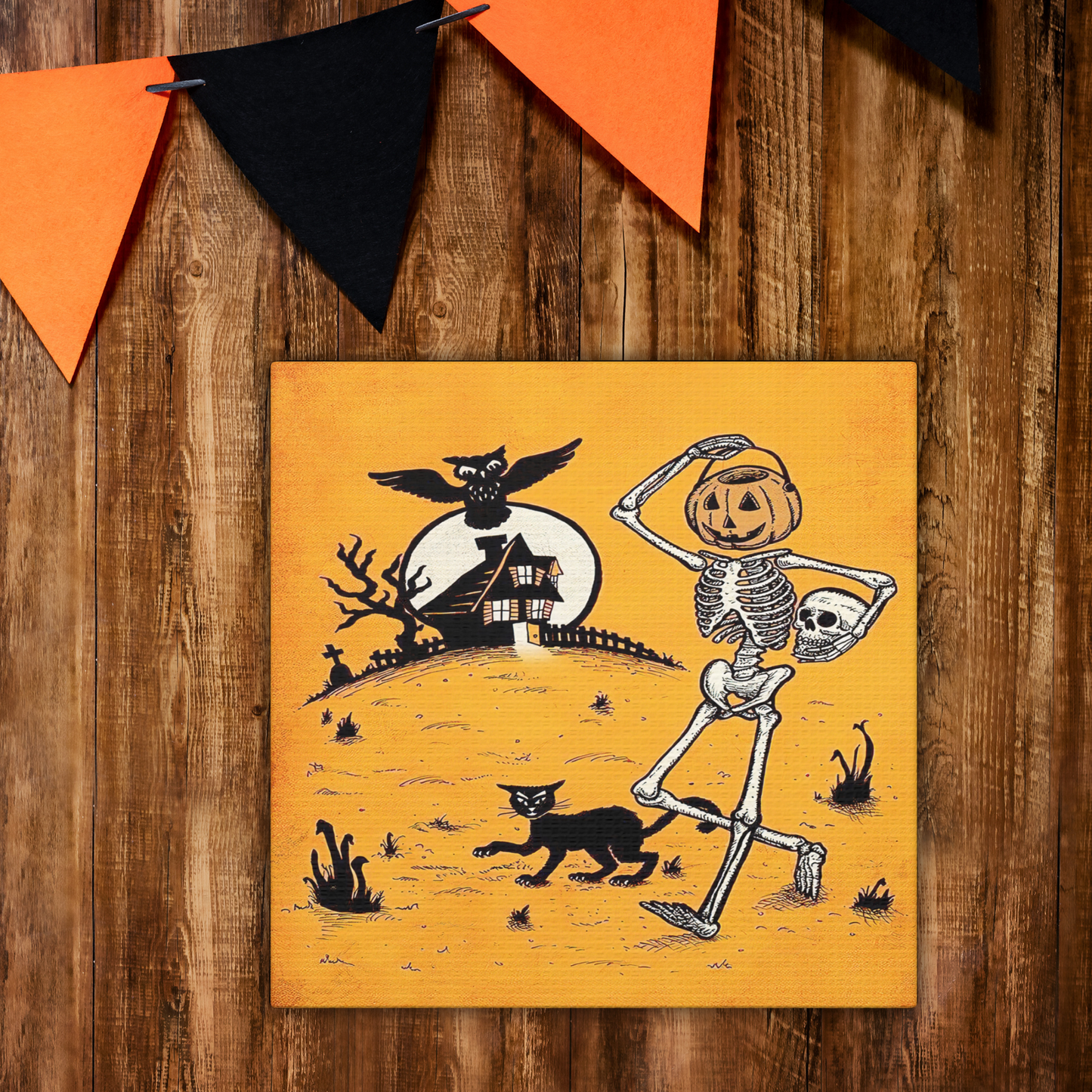 This canvas wall art features a retro vintage Halloween illustration of a skeleton with a trick or treating bucket for a head, a black cat, flying owl and spooky house with a full moon. The background is yellowish orange.