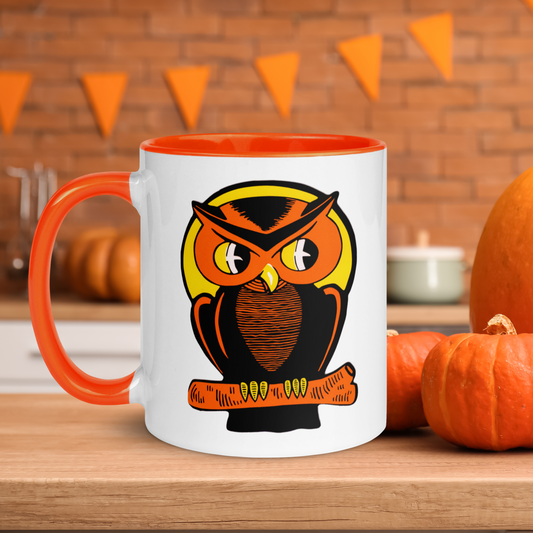 This glossy ceramic mug features a retro Halloween print of an orange owl perched on an orange branch with a yellow moon behind his head. The handle and inside of the mug is lined in orange.