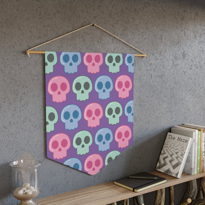 This fabric wall hanging features pastel skulls in pink, green and blue with a purple background. They are staggered in a pattern.