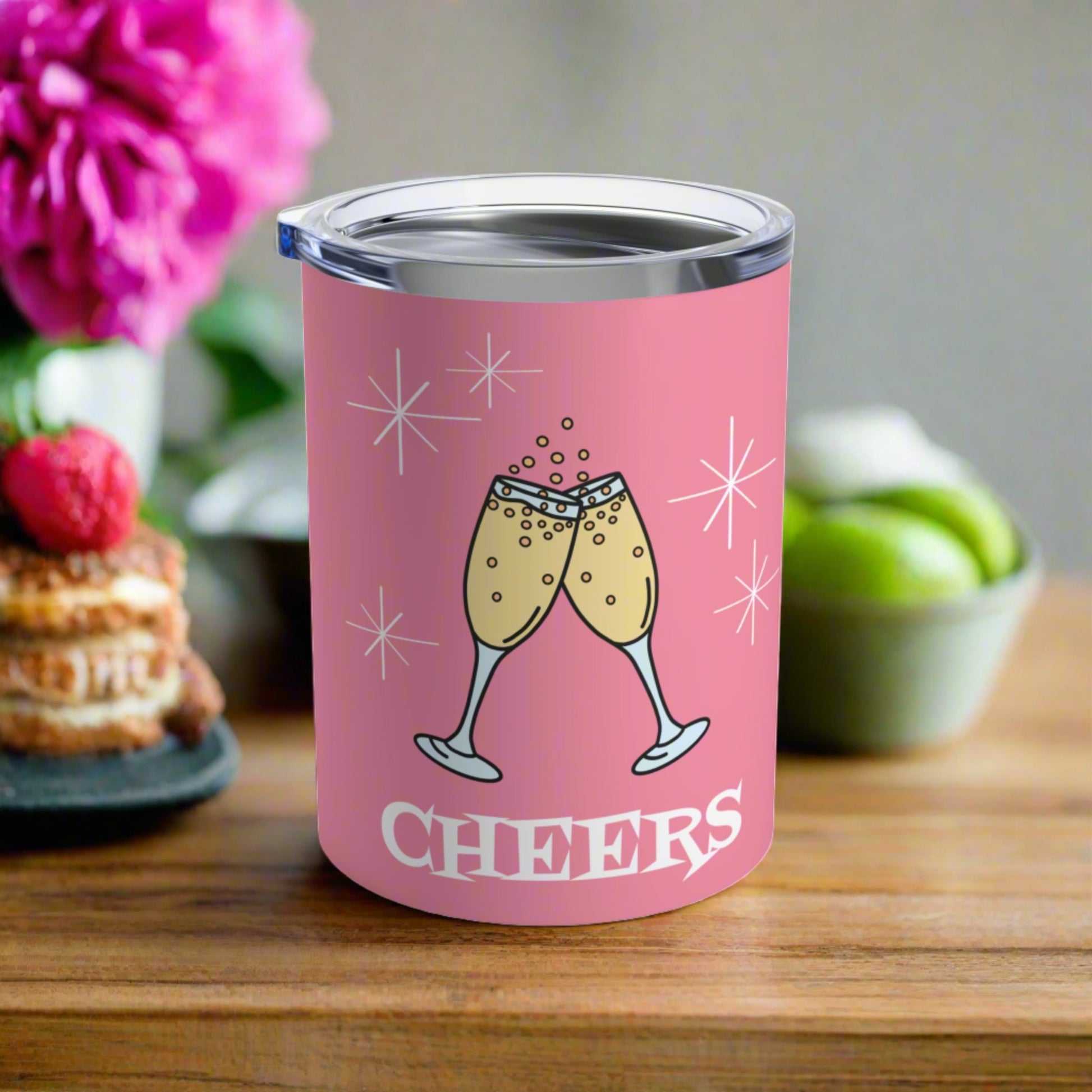 This 10 ounce pink stainless steel tumbler features two toasting champagne glasses with little bubbles. There is atomic era stars and lettering that says Cheers. It comes with a plastic sipping lid.