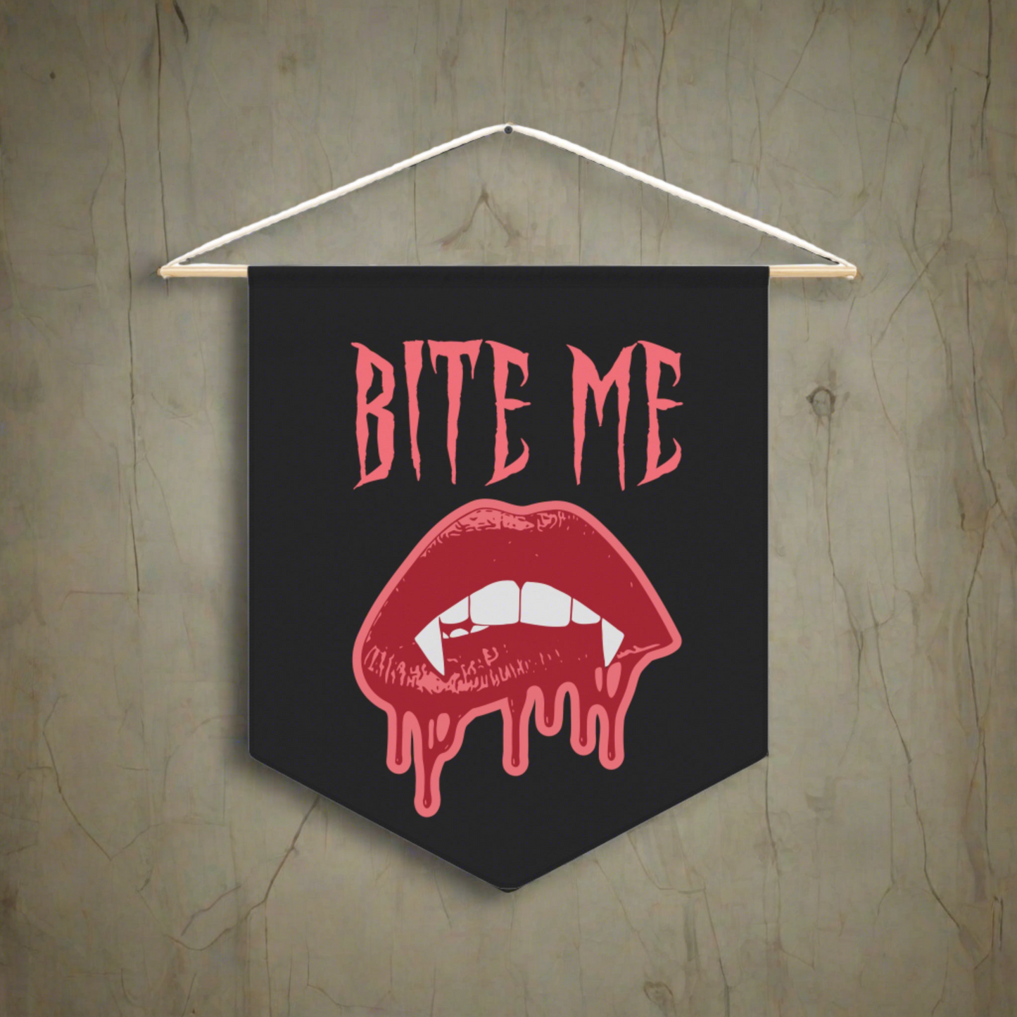 This pennant banner wall hanging features pink gothic lettering that says Bite Me with vampire lips and fangs dripping with blood beneath. 