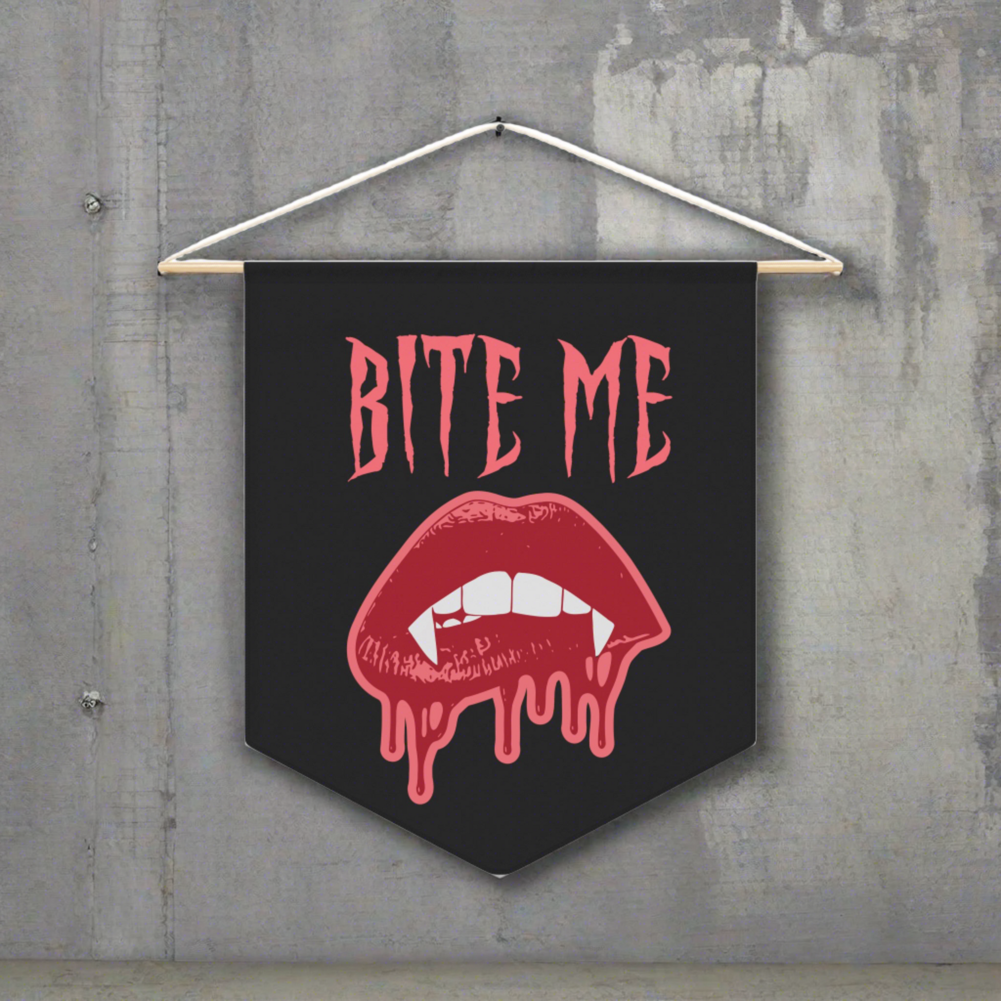 This pennant banner wall hanging features pink gothic lettering that says Bite Me with vampire lips and fangs dripping with blood beneath. 