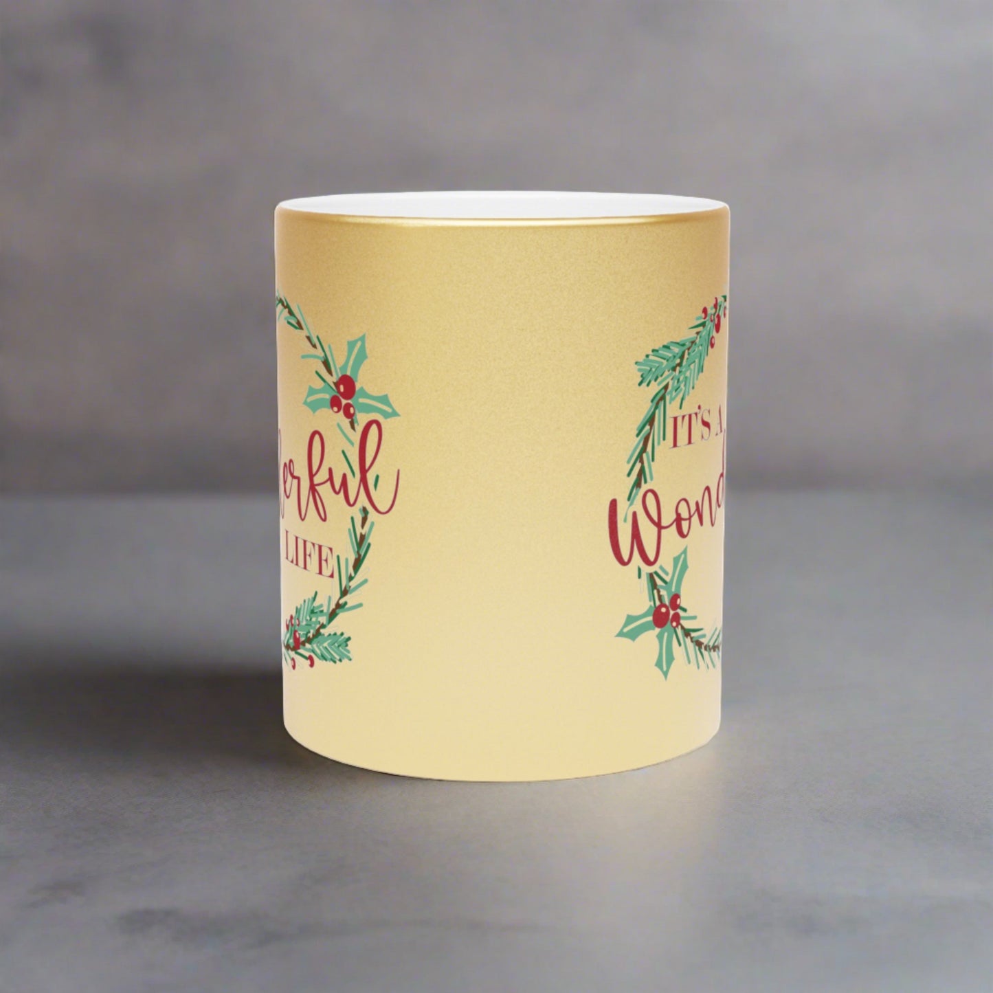 This gold metallic ceramic mug features a holly wreath with red lettering that says It's a Wonderful Life.