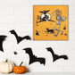 This canvas wall art features a retro vintage Halloween illustration of a skeleton with a trick or treating bucket for a head, a black cat, flying owl and spooky house with a full moon. The background is yellowish orange.