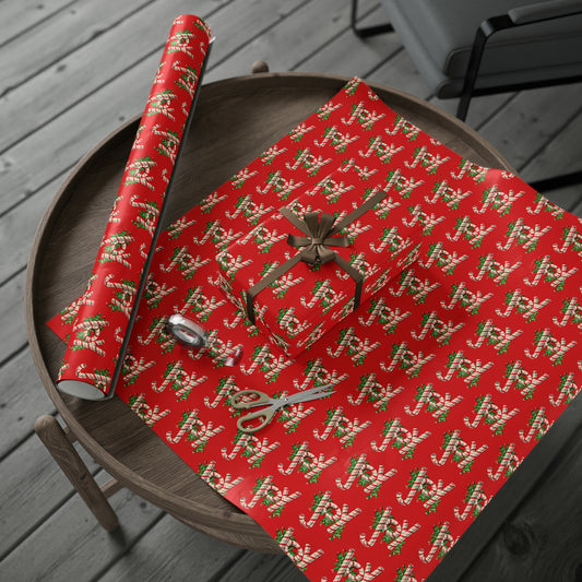 This retro vintage red Christmas wrapping paper features candy canes that spell out Joy with holly leaves behind them.