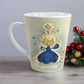 This ceramic glossy latte mug features an angel dressed in blue standing on a cloud. Her back is to us and you can see her wings. She is standing under a yellow star and bluebird. There are smaller white and blue stars and bluebirds surrounding her.