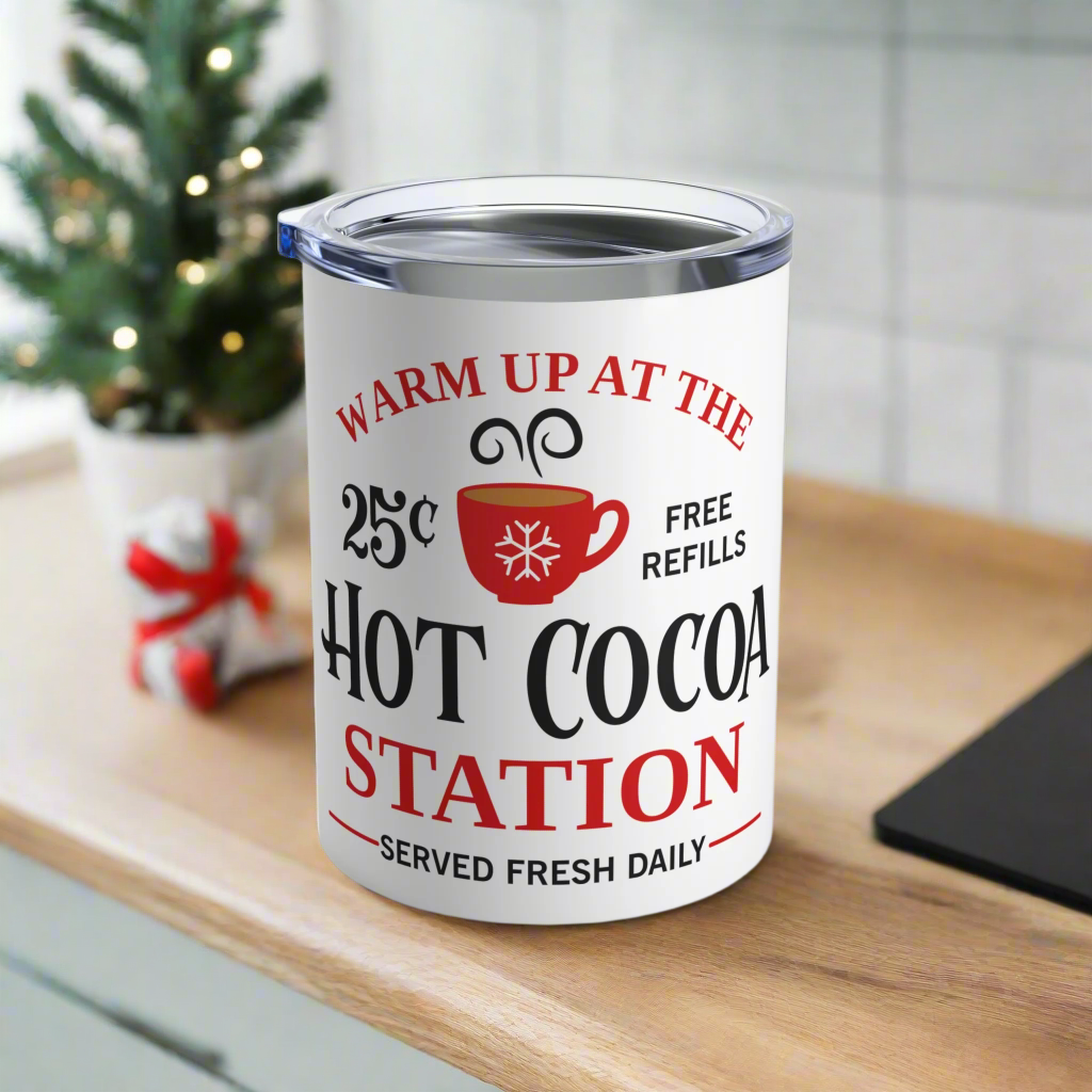 This white 10 ounce stainless steel tumbler mug says Warm Up At The Hot Cocoa Station Served Daily. 25 cent free refills. There is a little red coffee cup with a snowflake on it.