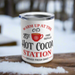 This white 10 ounce stainless steel tumbler mug says Warm Up At The Hot Cocoa Station Served Daily. 25 cent free refills. There is a little red coffee cup with a snowflake on it.