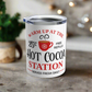 This white 10 ounce stainless steel tumbler mug says Warm Up At The Hot Cocoa Station Served Daily. 25 cent free refills. There is a little red coffee cup with a snowflake on it.