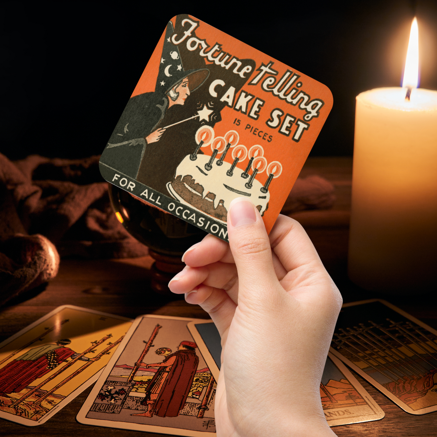 This square cork-back coaster features a retro Halloween illustration that says Fortune Telling Cake Set 15 pieces. There is a witchholding a star magic wand that she is waving over her cake with candles.