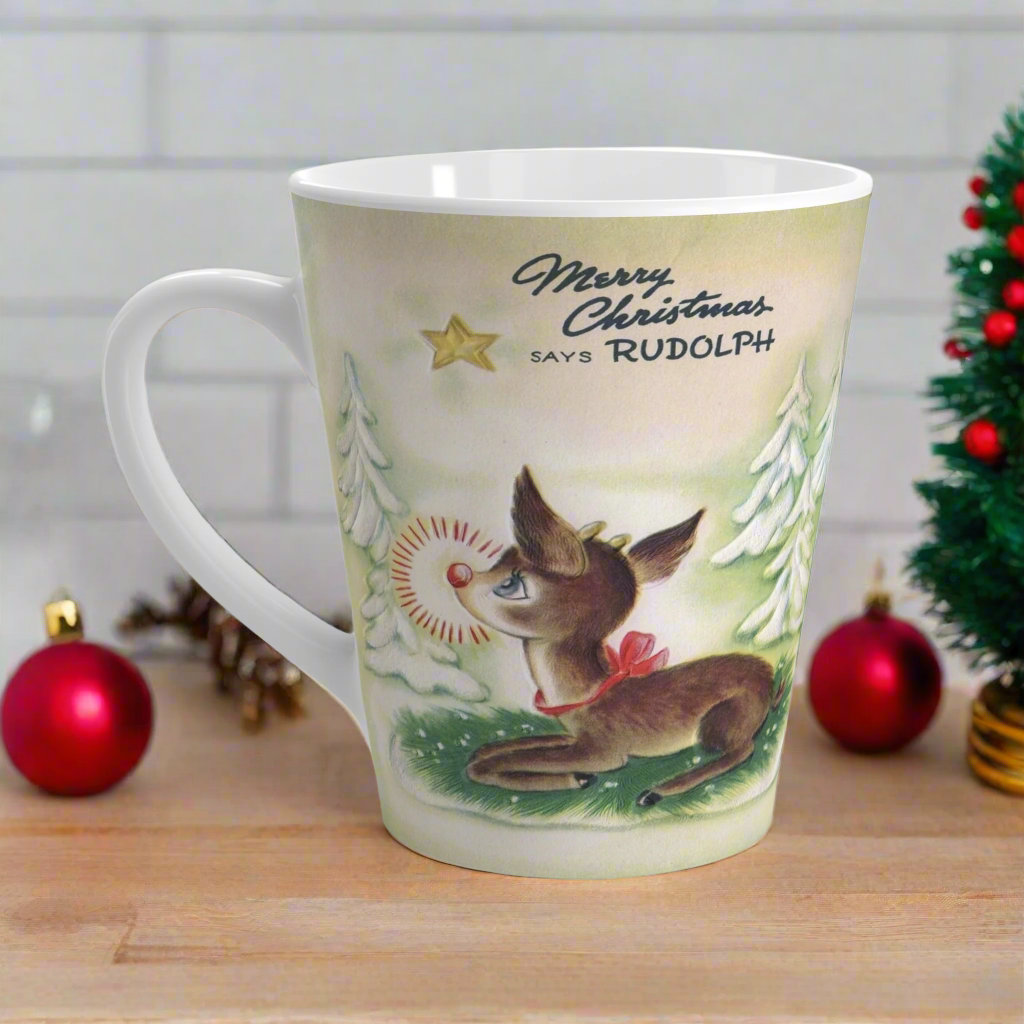 This ceramic latte coffee mug features a midcentury vintage Christmas illustration featuring Rudolph the Red Nosed Reindeer sitting down looking up at a gold star in the sky surrounded by snowy trees. It says: Merry Christmas Says Rudolph.