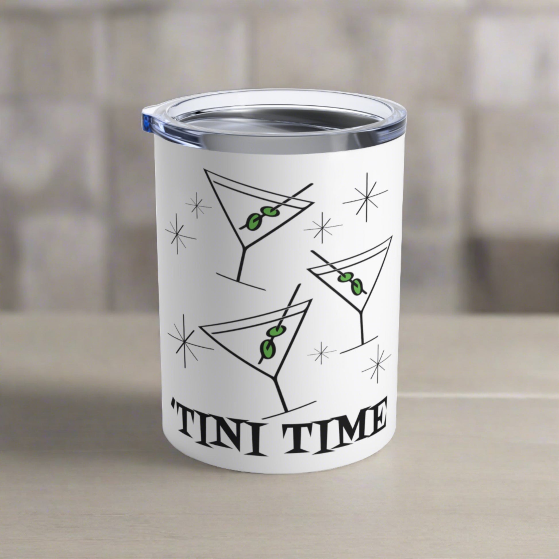 This 10 ounce white stainless steel tumbler features three martini glasses with green olives on toothpicks surrounded by stars and at the bottom the words say Tini Time in Atomic Retro Style lettering.