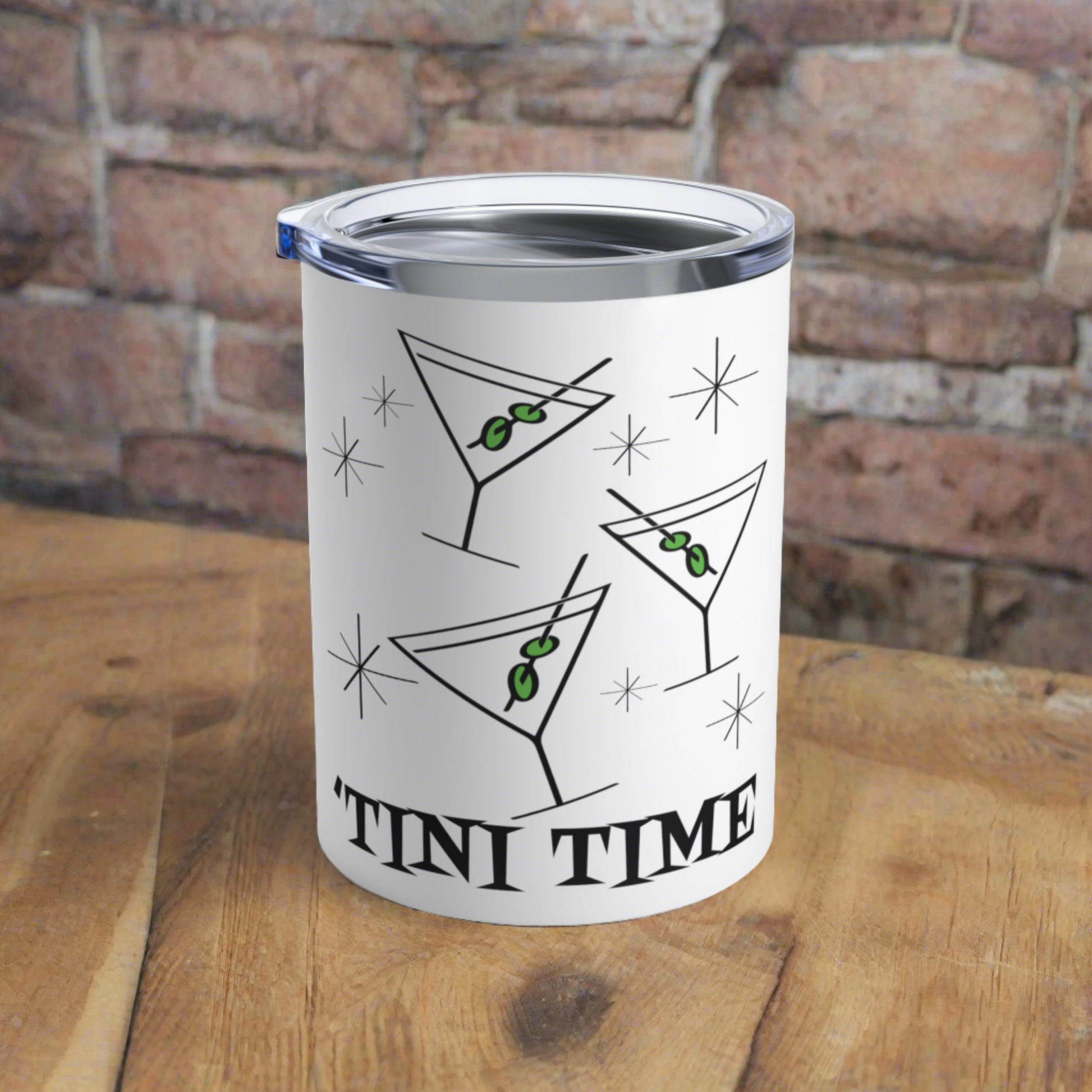 This 10 ounce white stainless steel tumbler features three martini glasses with green olives on toothpicks surrounded by stars and at the bottom the words say Tini Time in Atomic Retro Style lettering.