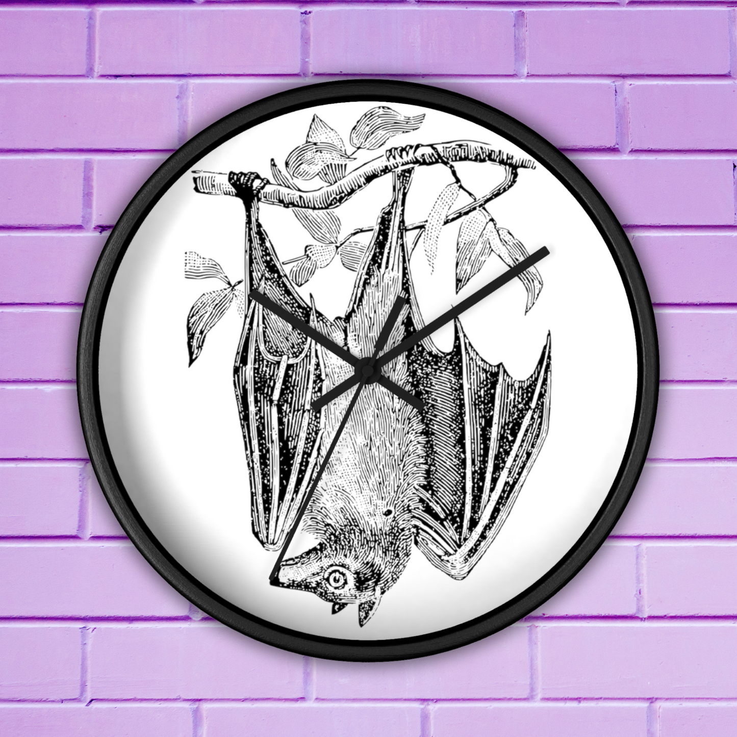 This black wall clock features a vintage illustration of a bat hanging upside down from a branch. The frame and hands of the clock are black.