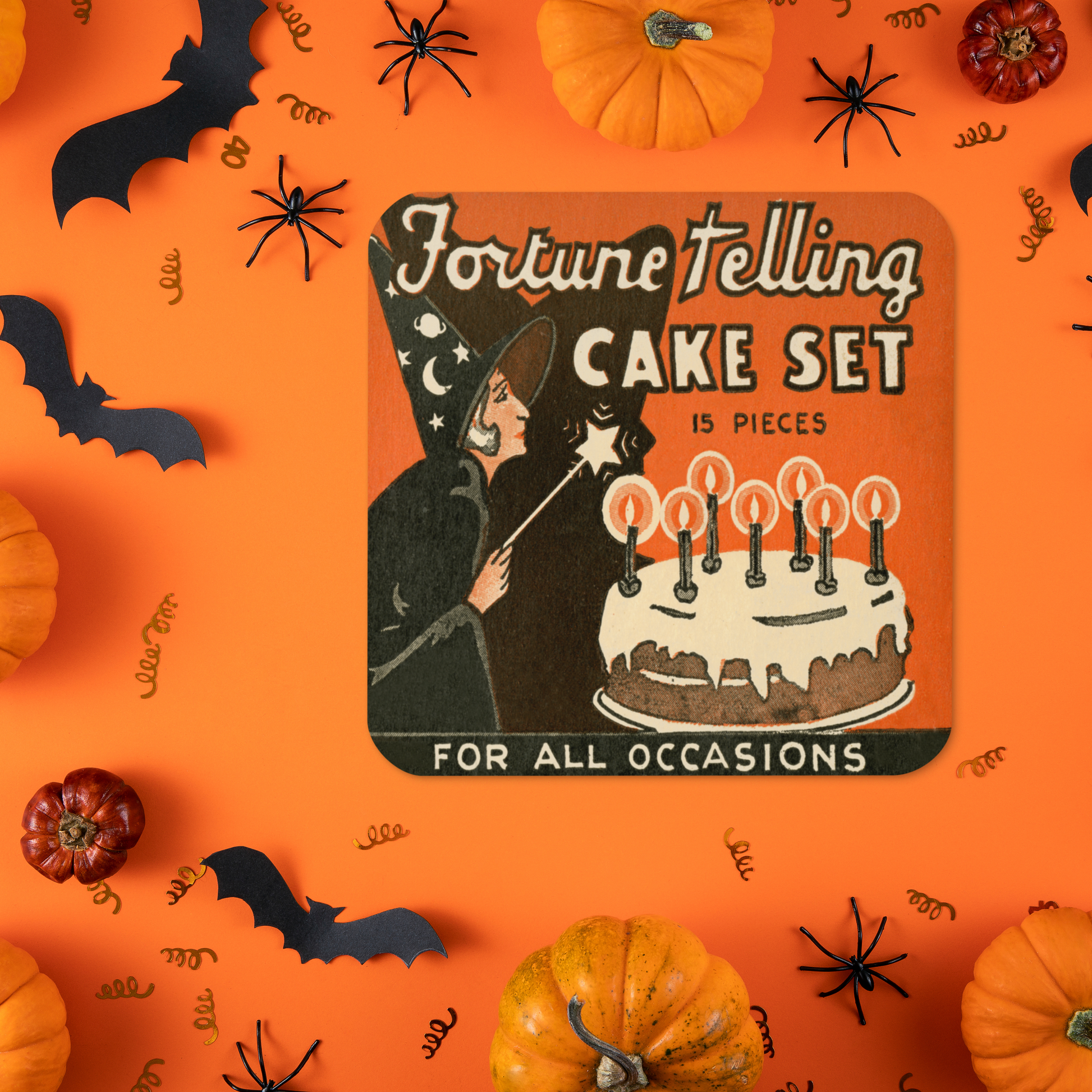 This square cork-back coaster features a retro Halloween illustration that says Fortune Telling Cake Set 15 pieces. There is a witchholding a star magic wand that she is waving over her cake with candles.