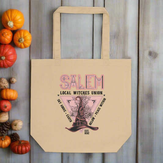 This large cotton eco tote features a Halloween design in pink and black that says Salem Local Witches Union. Sky Above Earth Below Peace Within. Est 1692. There is a pink triangle pointing downward and a pointy witch's hat.