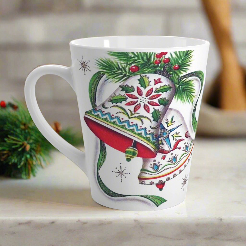 This ceramic glossy latte coffee cup features a vintage Christmas illustration of two holiday bells with ribbon, pine and berries. The design on the bells is reminiscent of European Scandinavian Christmas decorations.