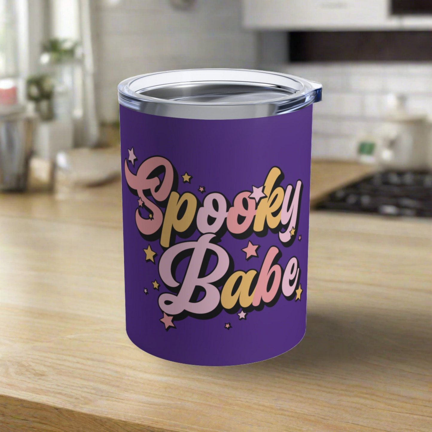 This 10 ounce purple stainless steel travel tumbler mug says Spooky Babe in pinks and yellows with stars.