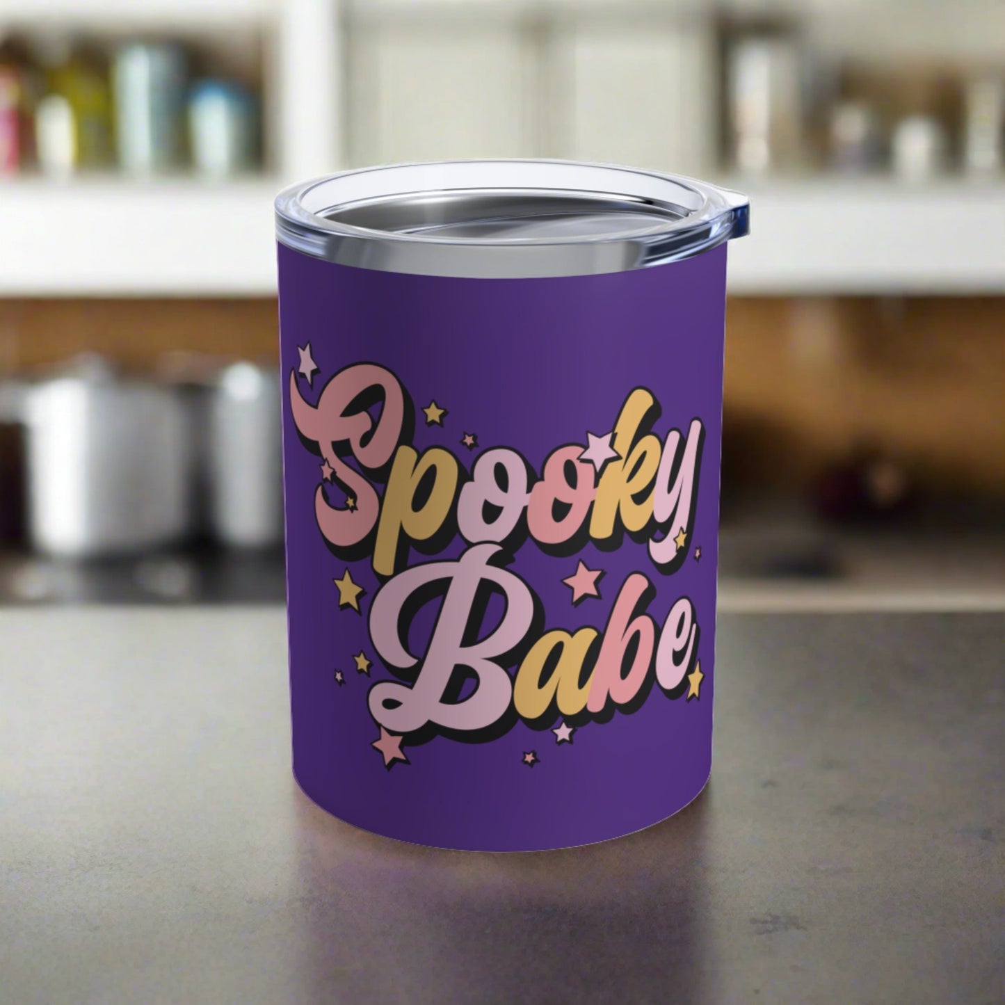 This 10 ounce purple stainless steel travel tumbler mug says Spooky Babe in pinks and yellows with stars.