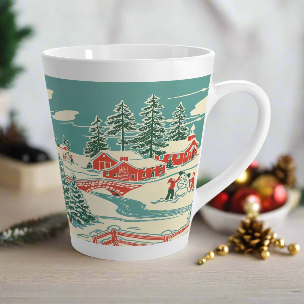 This ceramic glossy latte coffee mug features a vintage winter Christmas illustration of a snowy winter town. There are red houses, a bridge, trees, and two children building a snowman.